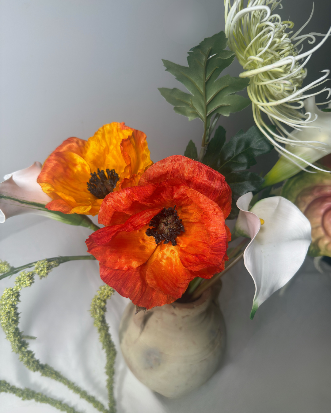 Close-up of real-touch orange poppy and white calla lily blooms in The Henry St Large arrangement — silk flower detail showing lifelike petal texture. Deadass Flowers NYC.