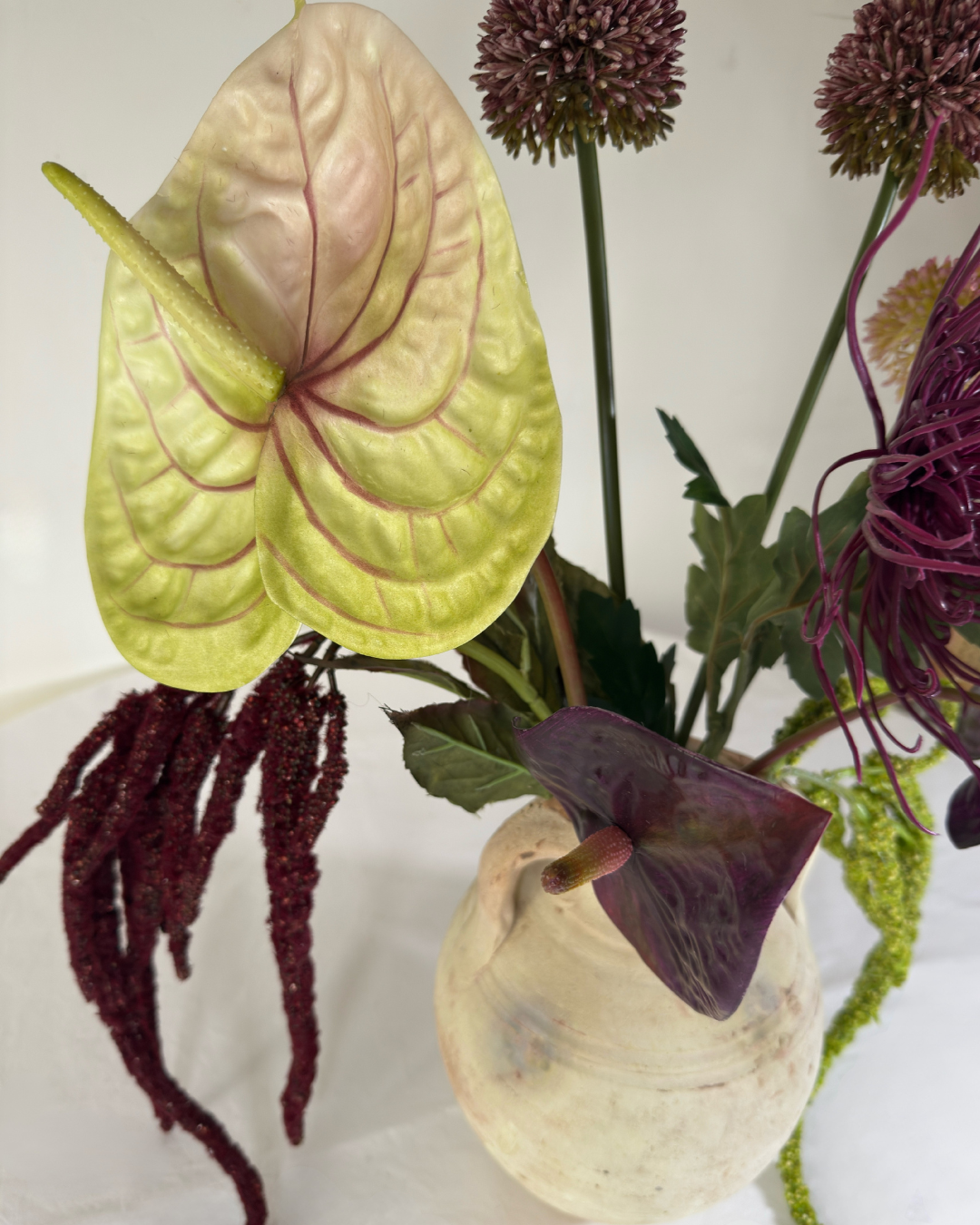 Close-up of purple anthurium and allium spheres in The Delancey Large real-touch silk arrangement.