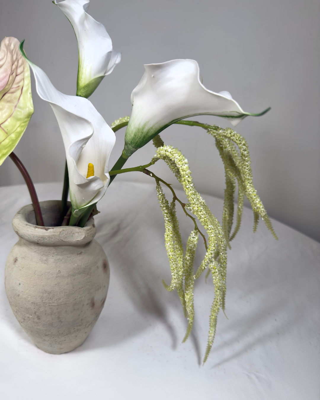 Close-up of white real-touch calla lilies and trailing amaranthus in The Sara J Mini silk arrangement.
