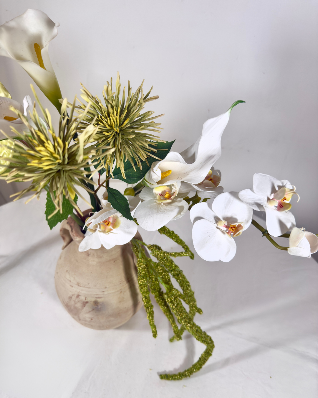 Close-up of white silk orchid and chrysanthemum blooms in The Sara J Large arrangement.